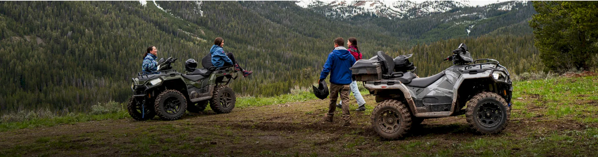 People gathered around two ATVs parked on a mountain trail